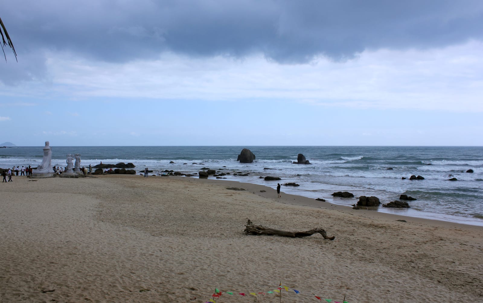 万宁日月湾沙滩、近岸礁石、海面与阴云天空